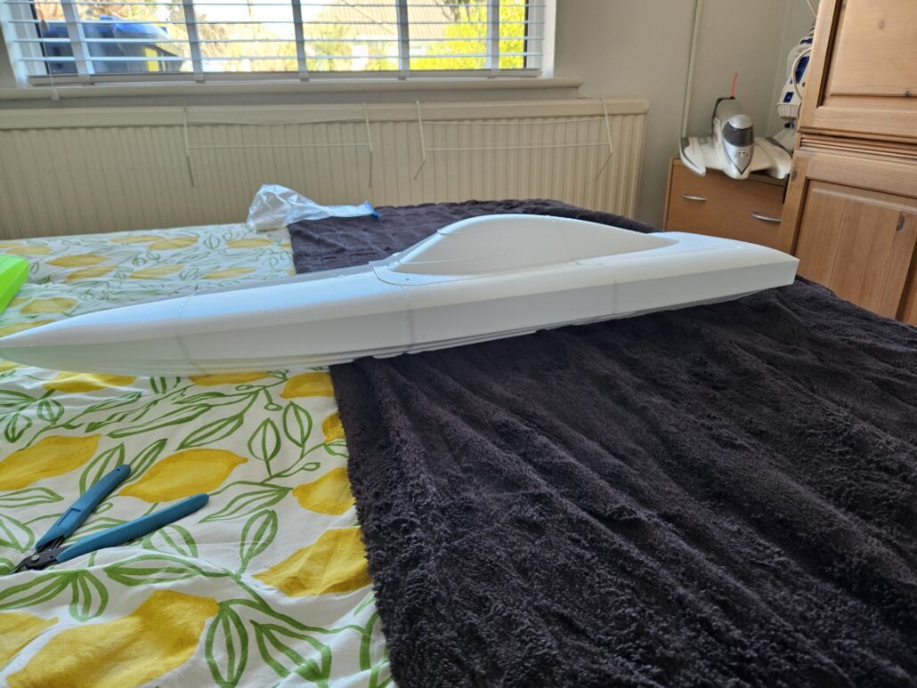 White 3d printed speedboat lying on a bed